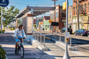 biker rides pass bus stop