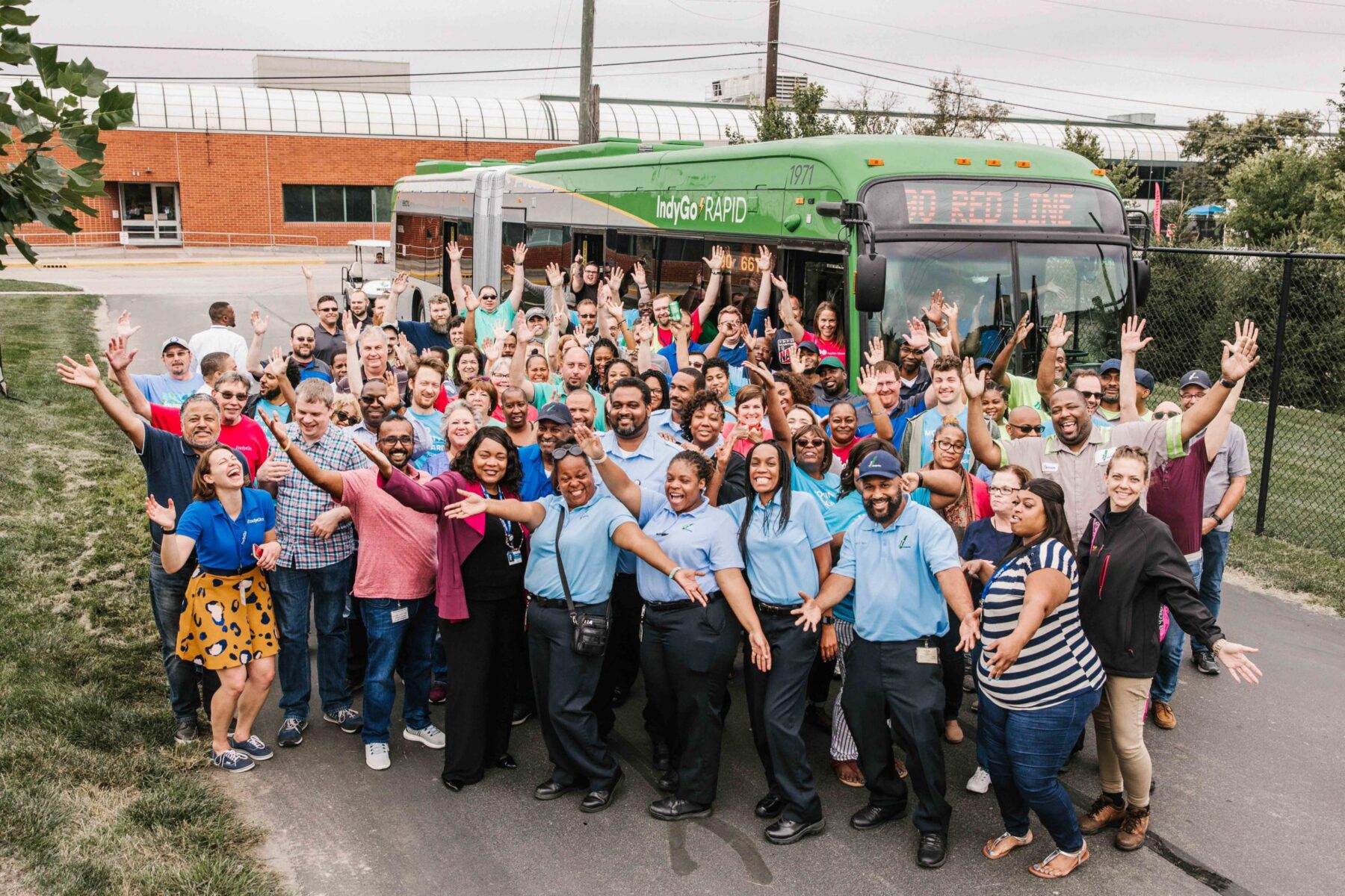 large group of indygo employess in front of a bus
