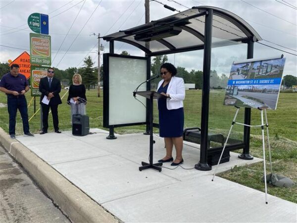 woman speaks to onlookers a bus stop