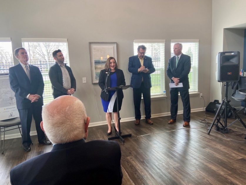 IPTF Executive Director Emily Lovison speaking at podium with Indianapolis Mayor Joe Hogsett and other from afar. 