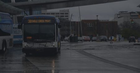IndyGo bus stopped at station on a rainy day.