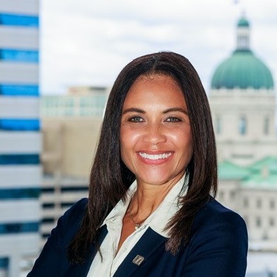 Businesswoman in suit and tie standing in front of city skyline.