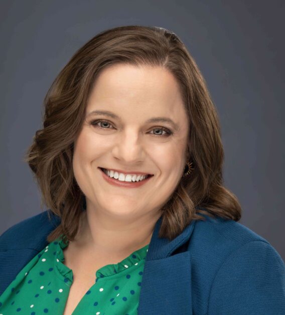 A woman with brown hair wearing a blue blazer.