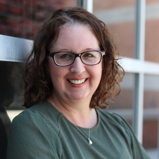 A woman wearing glasses and a green shirt.