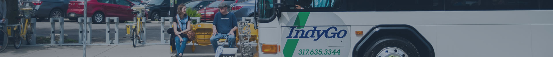 Man and Woman Sitting at Bus Stop as Bus Arrives