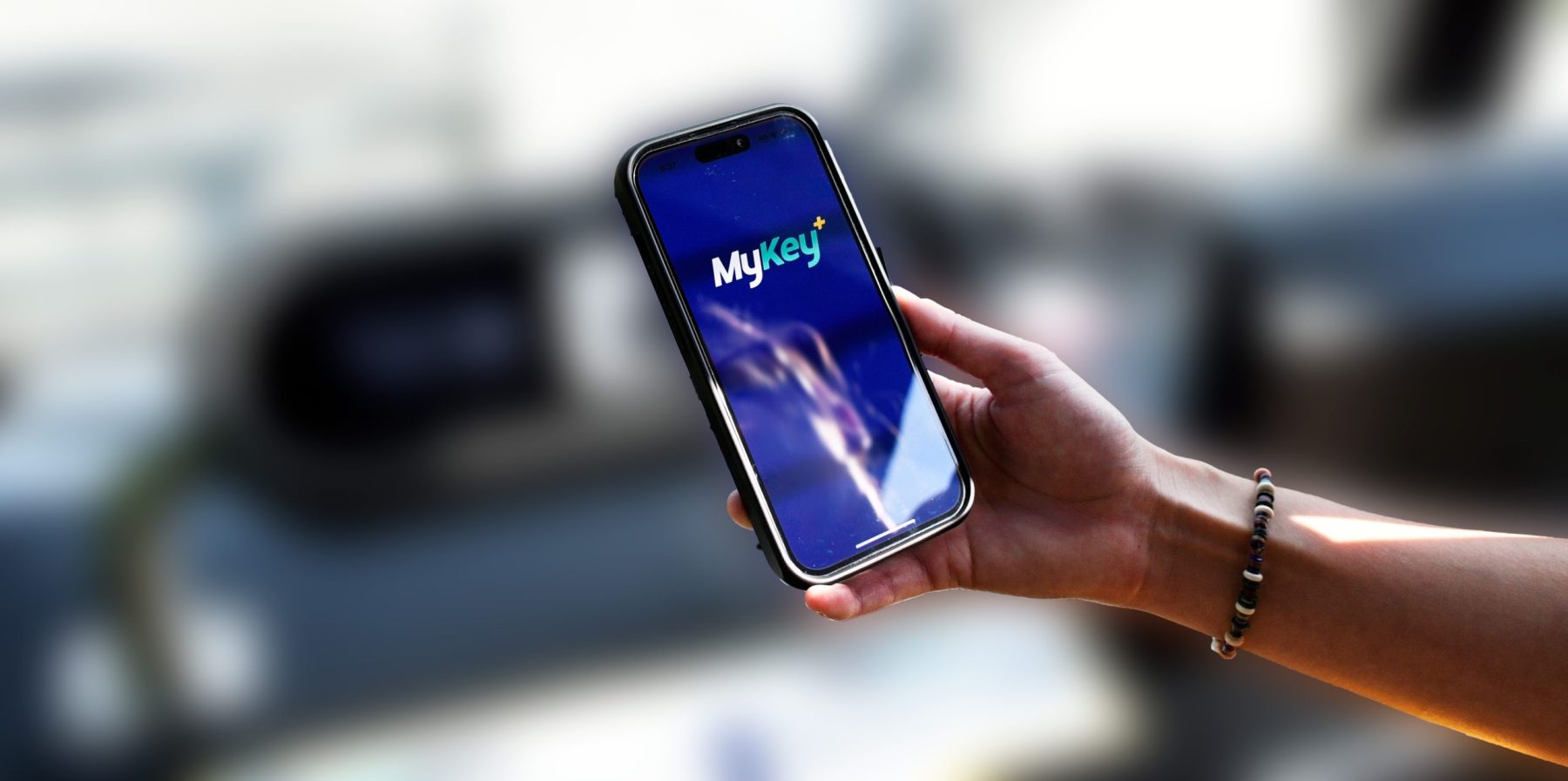 Hand holding a phone with the MyKey Plus App